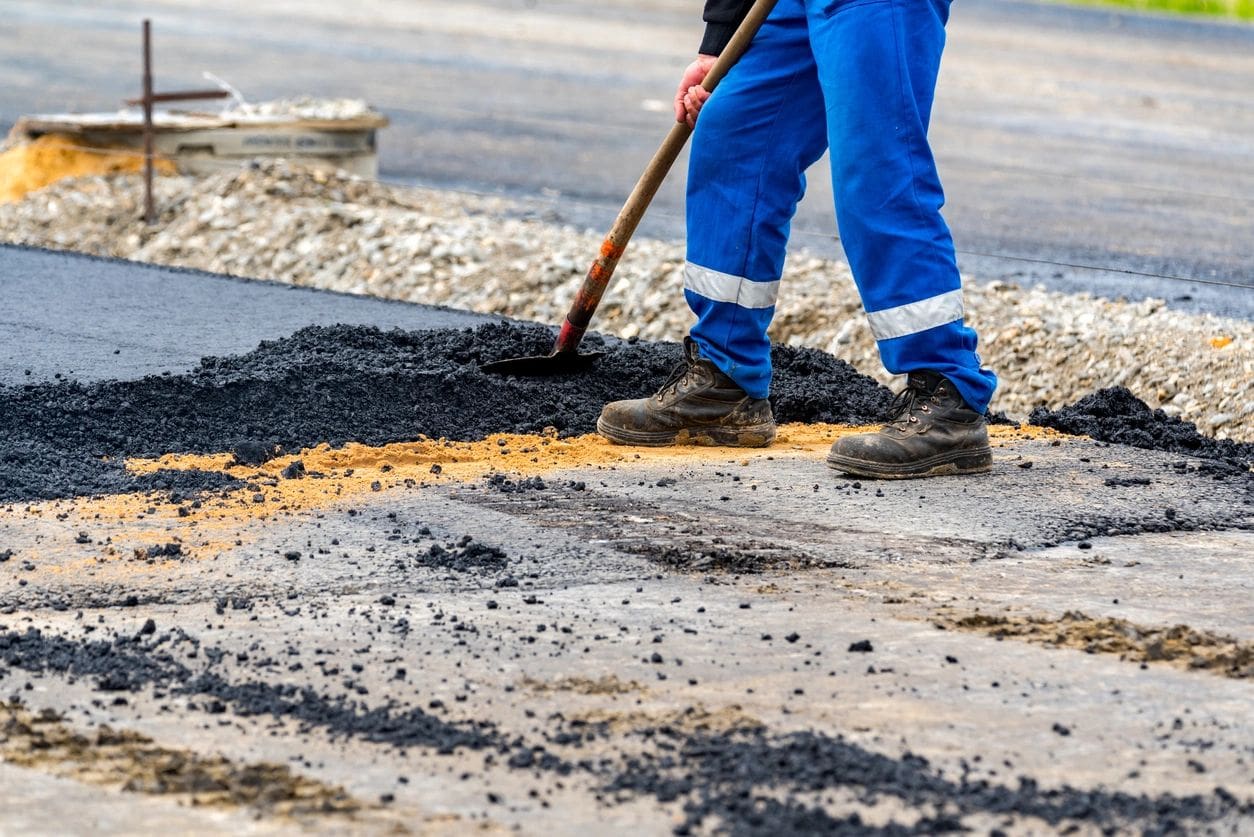 A person with a shovel is working on the road.